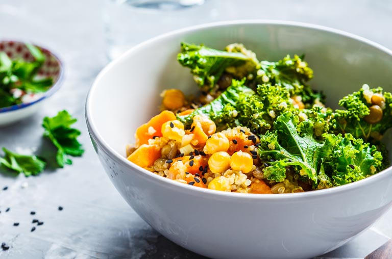Kale, corn, and a grain in a white bowl
